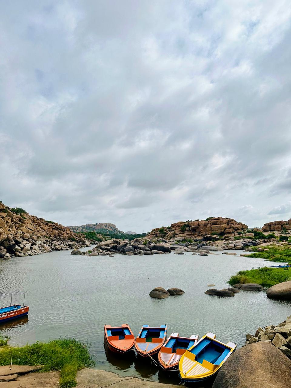 Colourful boats moored beside the Tungabhadra River among Hampi's boulders